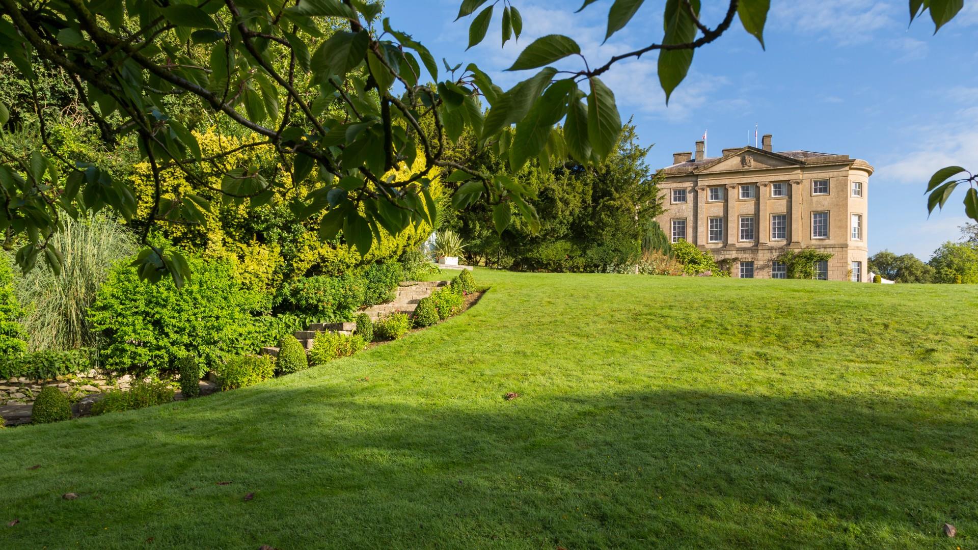 The American Museum manor is framed by the leaves of a tree