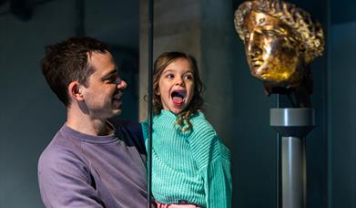 child and parent looking at statue of Minerva at The Roman Baths