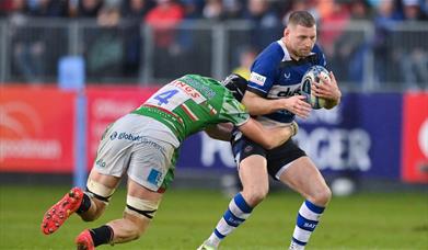 Bath Rugby player being tackled by an opposing team player