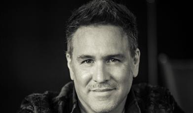 A black-and-white portrait of a smiling man with short greying hair.