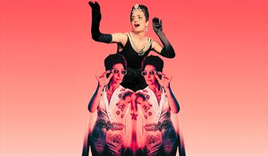 A performer in black with pearls and a tiara, arms raised, above a mirrored image of a performer in a jewelled white Elvis-stye jumpsuit.