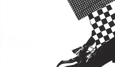 Black and white graphic of a loafer shoe with  checked houndstooth fabric, evoking a ska/2-tone aesthetic.