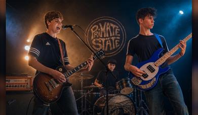 Band Primate State performing live on stage under moody lighting.