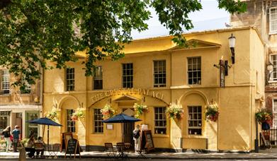 The exterior of The Crystal Palace, a pub with yellow walls and gold lettering above the entrance.