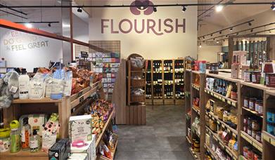 Inside of a farm shop with shelves of nice tinned/jarred products and a sign in the background that says 'Flourish'