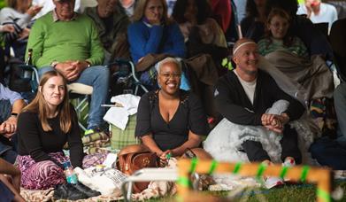 A group of people audience members smiling at the Garden Theatre Festival in Bath. 