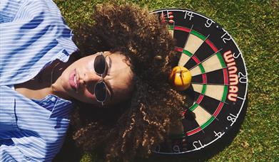 Person lying down on top of a dart board