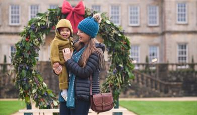 Woman and child having fun in front of a giant Christmas wreath