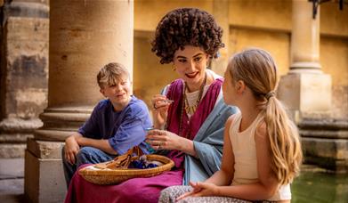 Two children speaking to a woman in Roman costume