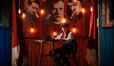 A person sits down at the table, it's nighttime, with photographs above. 