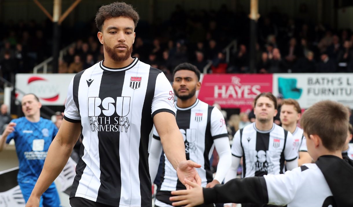 Bath City football player high fiving a child during a walk out onto the pitch