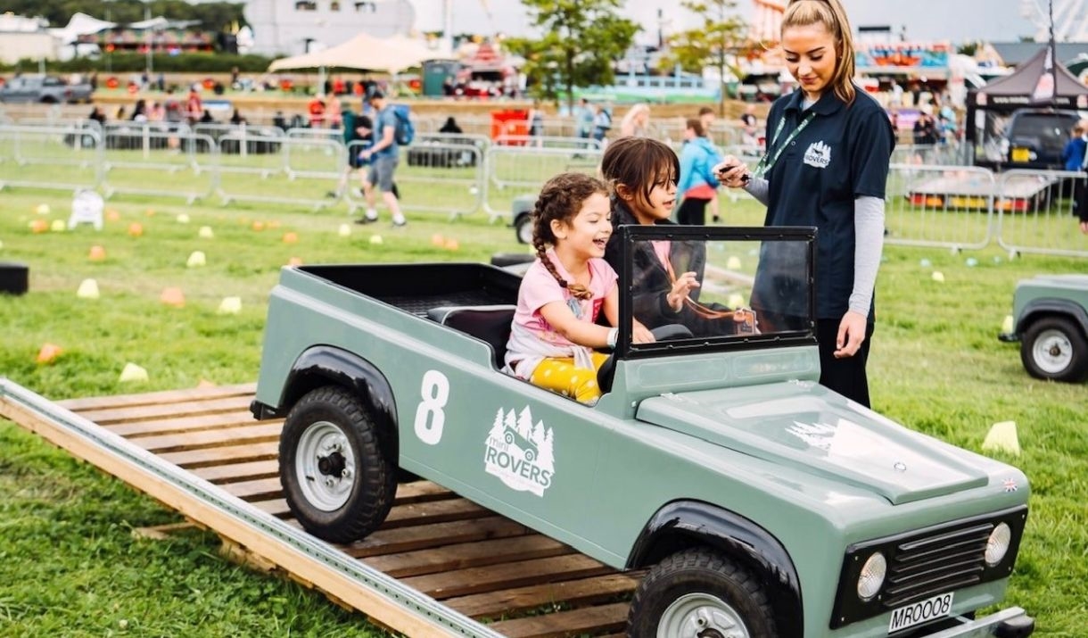 2 young children in a mint green mini land rover