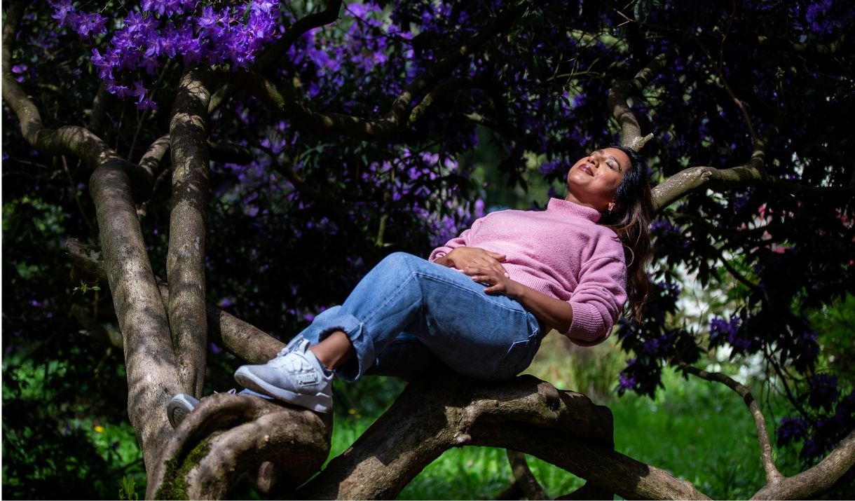 girl lying back on tree trunk