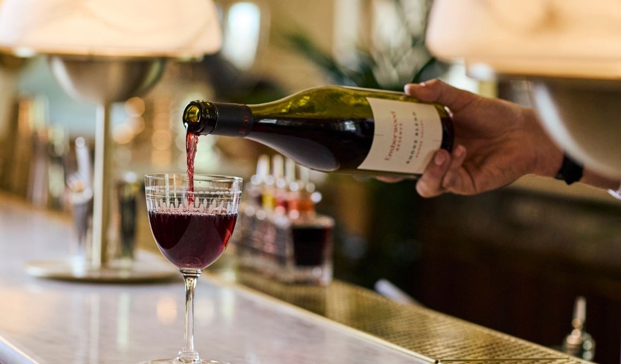 A hand pouring a bottle of red wine into a glass