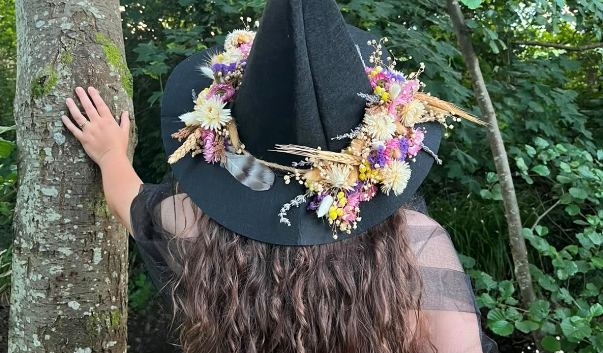 Woman wearing a floral witch hat in a forest