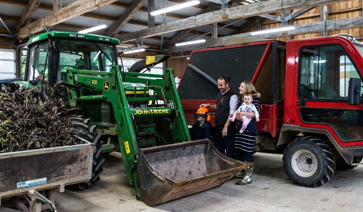 family looking at agricultural vehicles in large shed