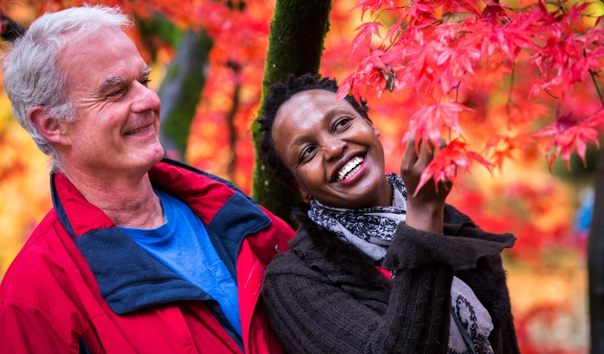 couple gaze up into red and orange leaved tree