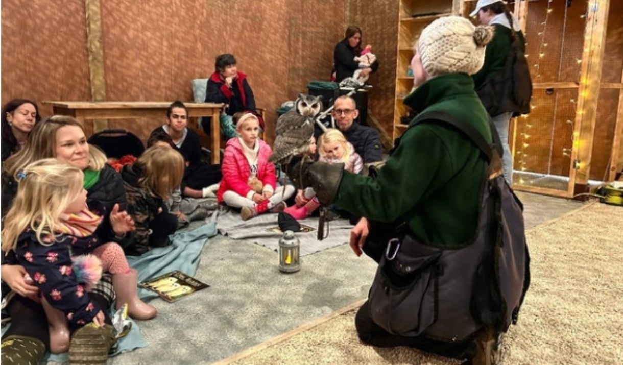 A bird keeper holds an owl close to children and their parents for them to see