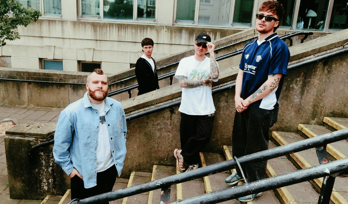Four band members pose on concrete steps outside a city building.