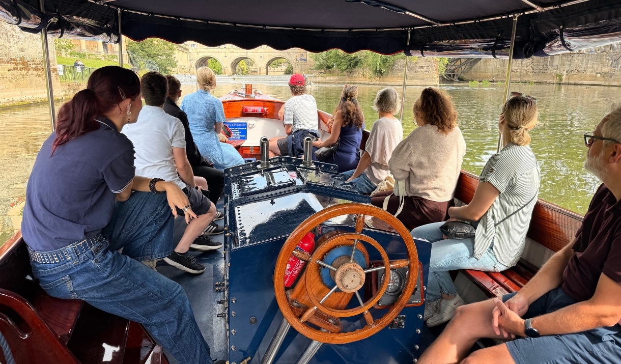 A group sat on a boat cruising on the River Avon