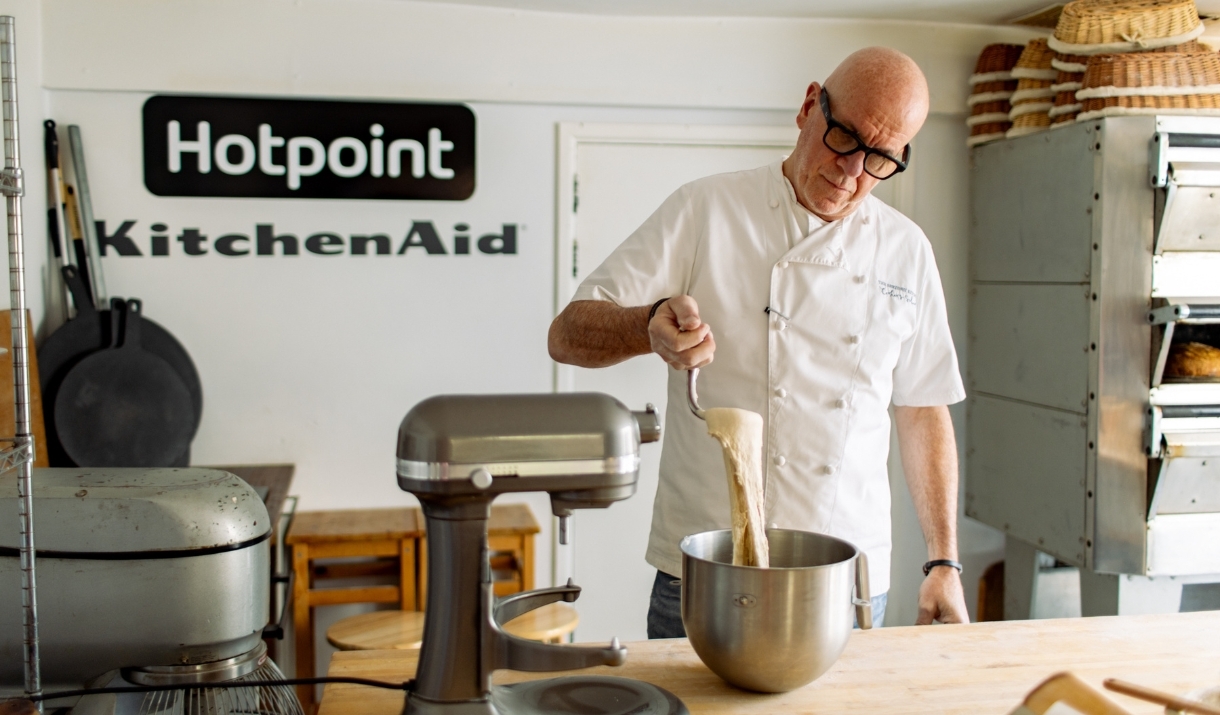 Richard Bertinet, wearing a white chef's coat, pulls batter from the bowl of a KitchenAid stand mixer.