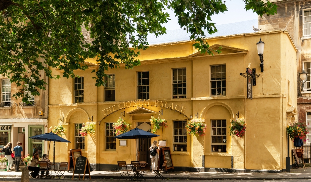 The exterior of The Crystal Palace, a pub with yellow walls and gold lettering above the entrance.