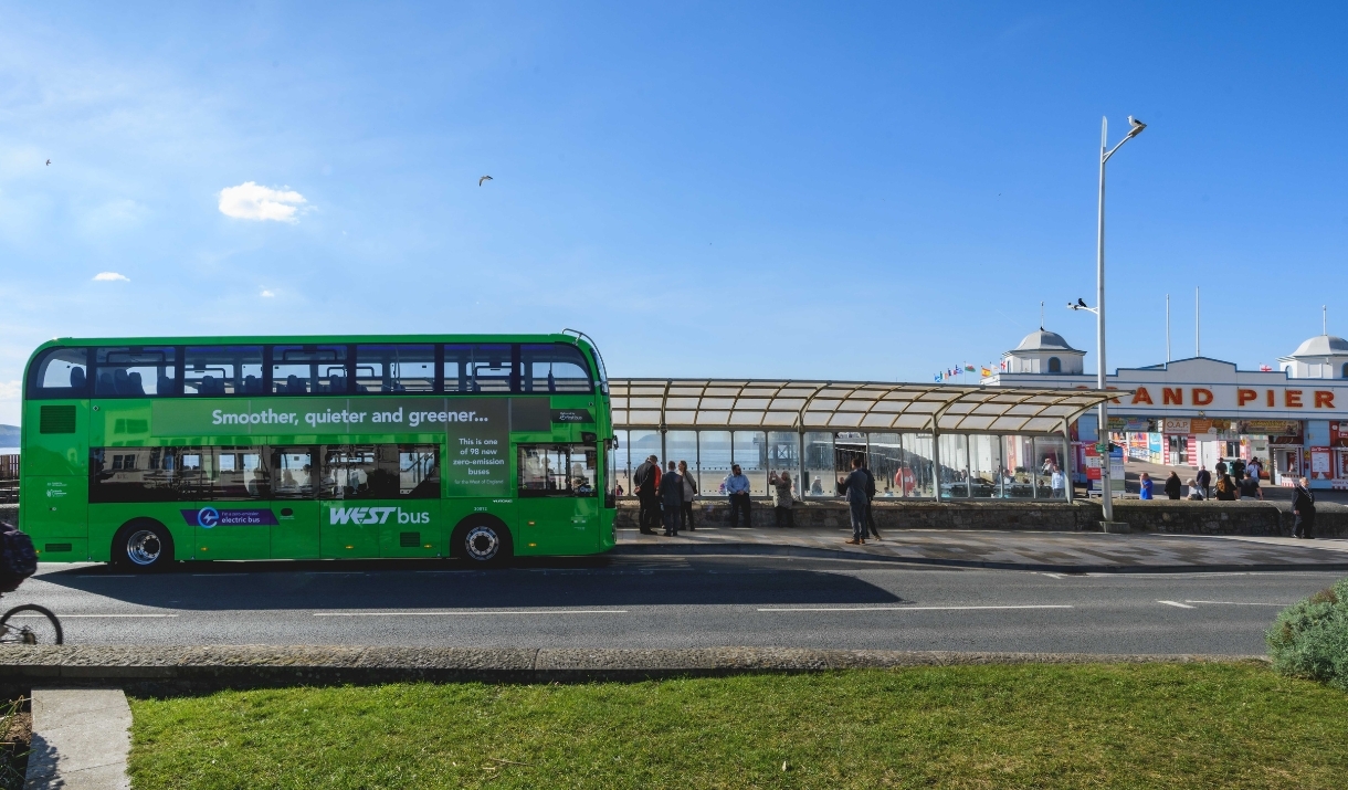 A green-coloured fully electric double decker bus owned by First Bus parked outside The Grand Pier in Weston-super-Mare, North Somerset