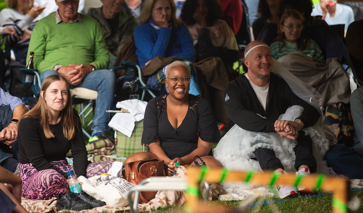 A group of people audience members smiling at the Garden Theatre Festival in Bath.