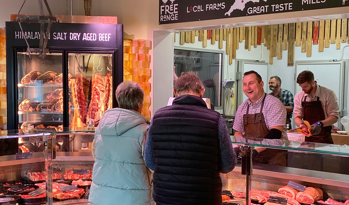 Two people buying meat from a butchers counter in the farm shop