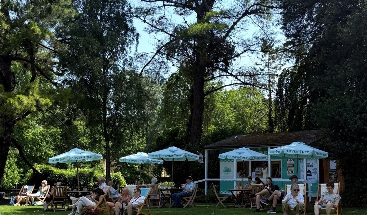 Customers enjoy the House of Friends park cafe, sat on deckchairs under parasols in the Parade Gardens park