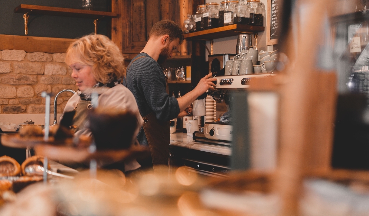 Two baristas serving customers behind the bar at Iford Manor Cafe
