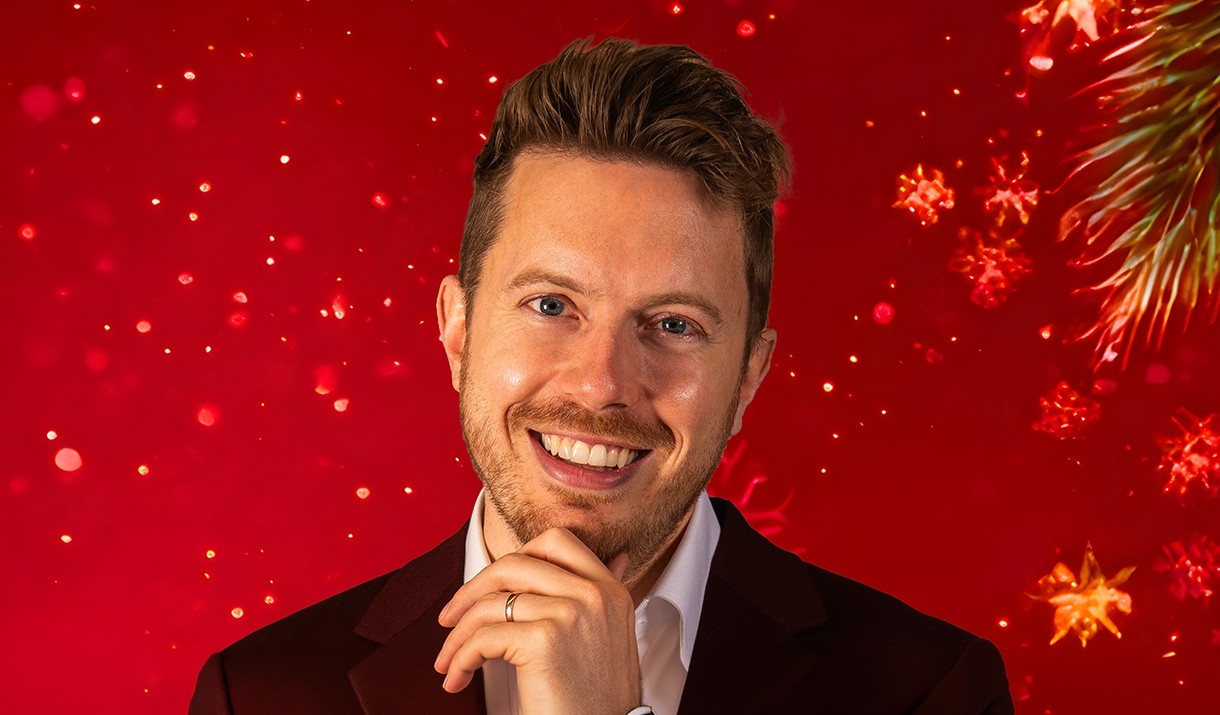 A man smiling with a hand resting on his chin, set against a red background with sparkles.