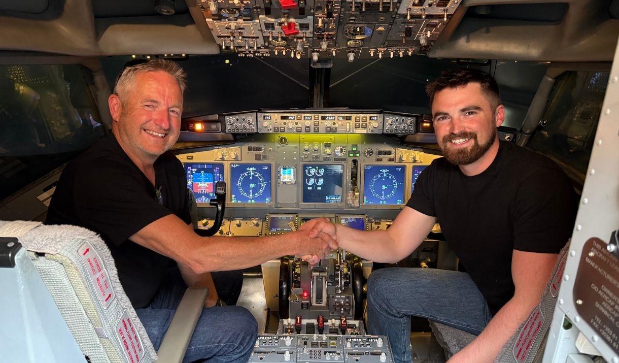 Two men sat inside a jet flight simulator