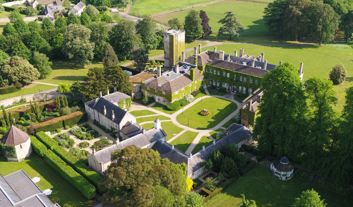 Aerial photo of a large estate with surrounding gardens, fields and trees.