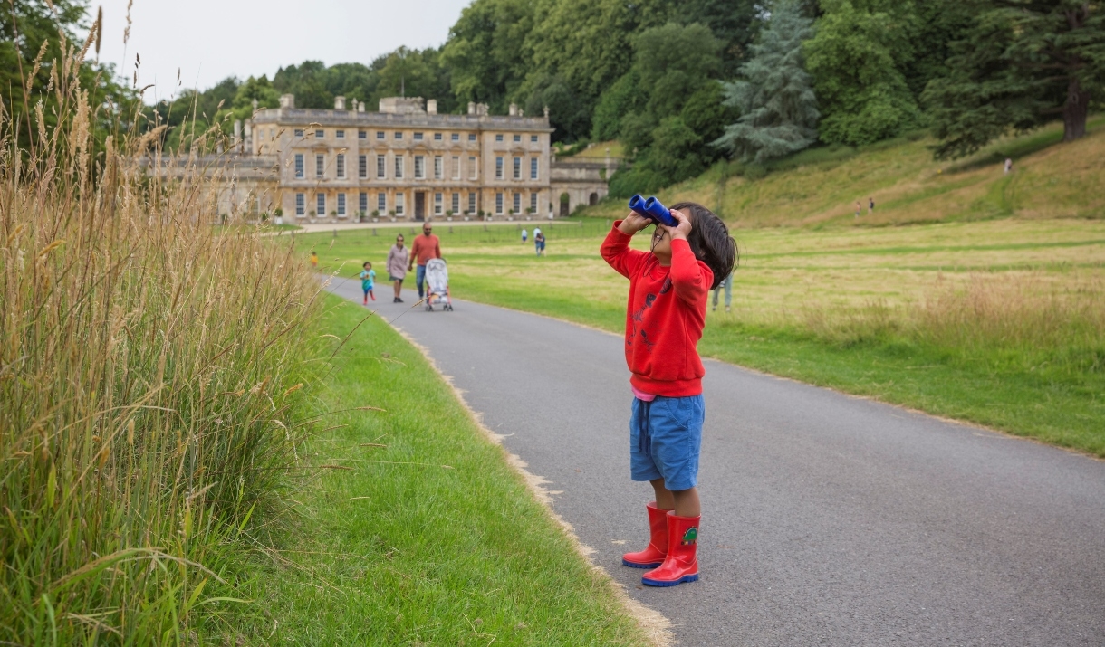 Child with binoculars looking up into parkland