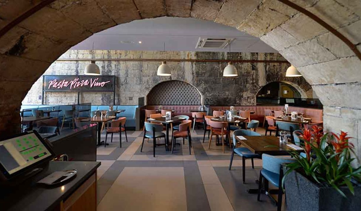 The interior dining area at Prezzo Bath, with arched stone ceiling and exposed brick walls.