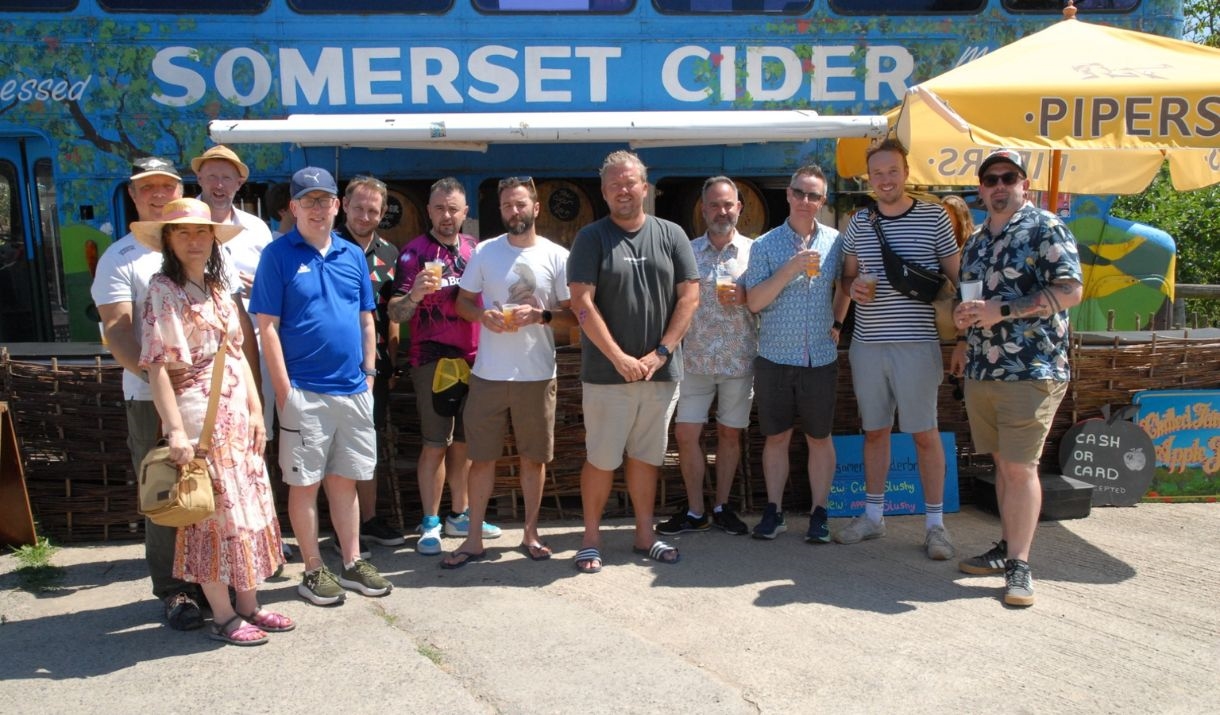Tour group stood in front of a bus with "Somerset Cider" written on the side.