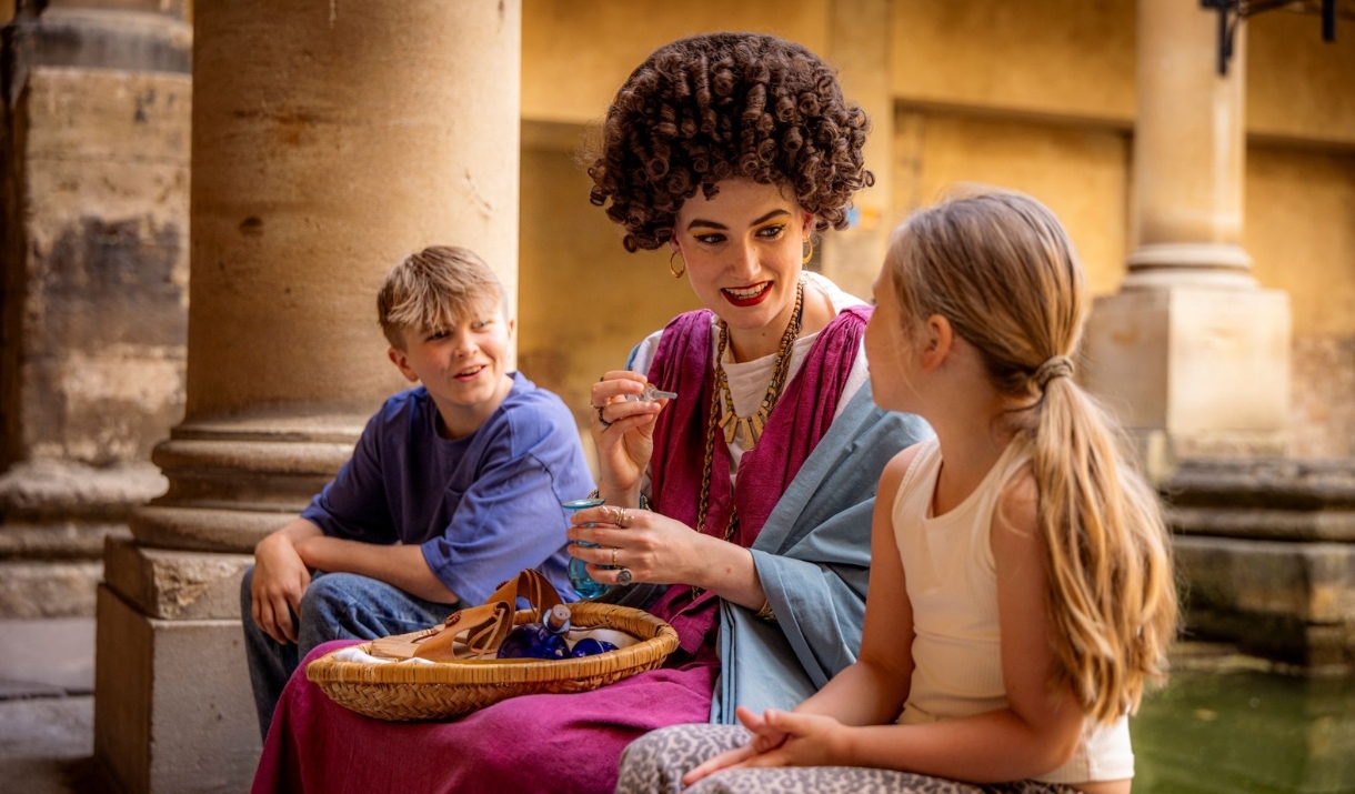 Two children speaking to a woman in Roman costume