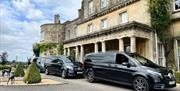 Three luxury black minivans parked in a line in front of Lucknam Park Hotel and Spa