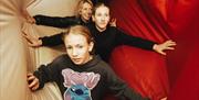Two children and an adult pushing through plush fabric walls