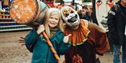 A child posing for the camera alongside a creepy clown with a large mallet.