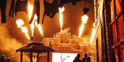 Fire show at Avon Valley FEAR event, with jets of flame erupting from the top of a tall stage in several directions.