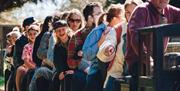 A line of adults and children sat on a miniature railway train