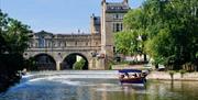 The Jolly Brit boat sailing away from Pulteney Weir on the River Avon
