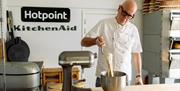 Richard Bertinet, wearing a white chef's coat, pulls batter from the bowl of a KitchenAid stand mixer.