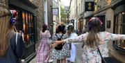 A group of people wearing silent disco headphones, walking away from the camera down an alleyway in Bath.