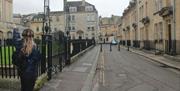 A person wearing silent disco headphones walking away from the camera down a street in Bath.