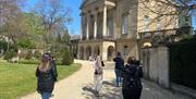 A group wearing silent disco headphones walks towards the Holburne Museum in Bath.