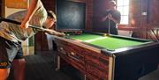 Two men playing pool inside The Lodge at Bucklegrove Holiday Park