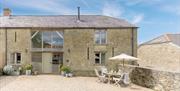 The exterior of Hatts Barn, a large modern cottage with outdoor dining space.
